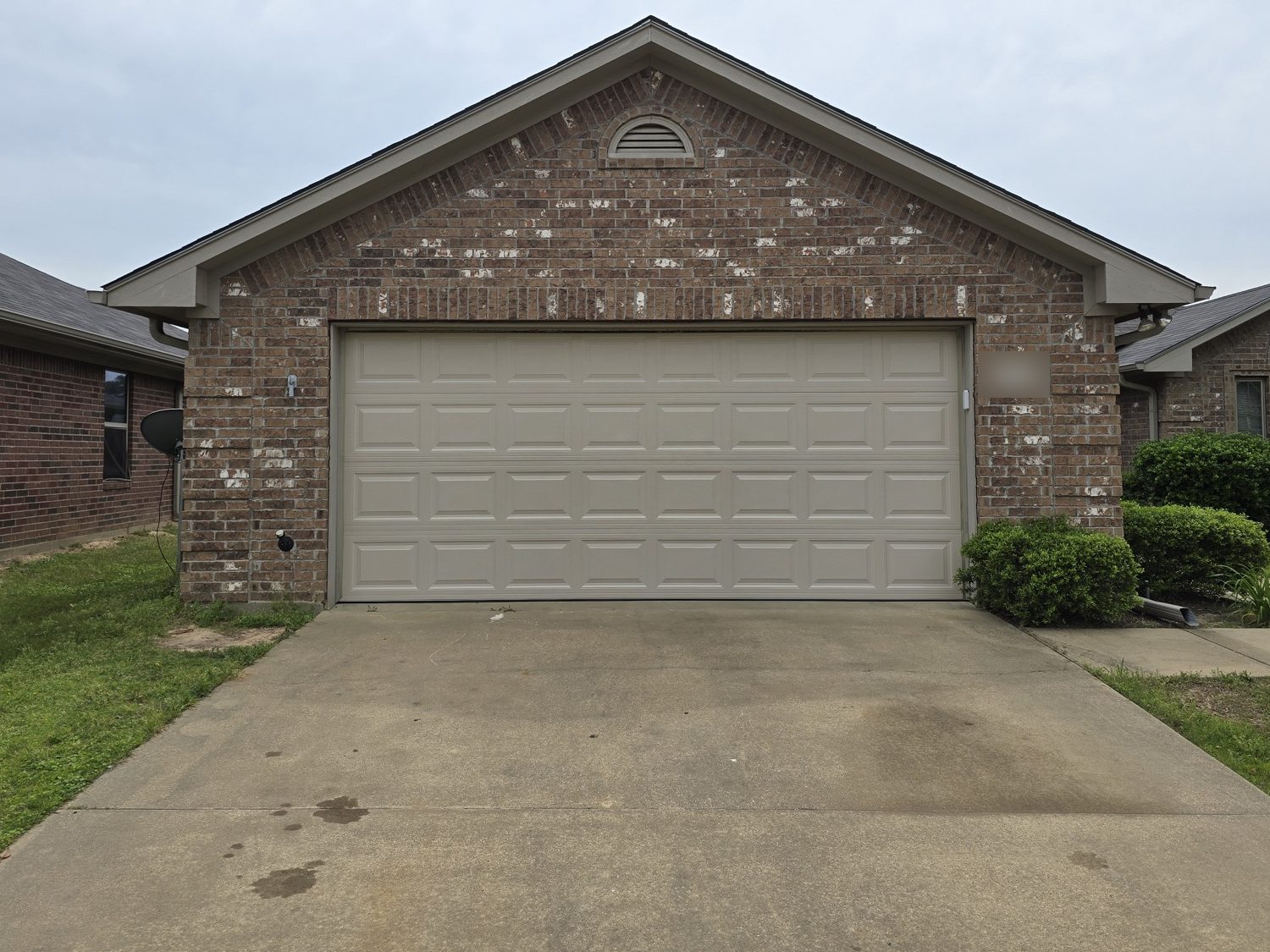 A new tan raised-panel garage door on a brick house