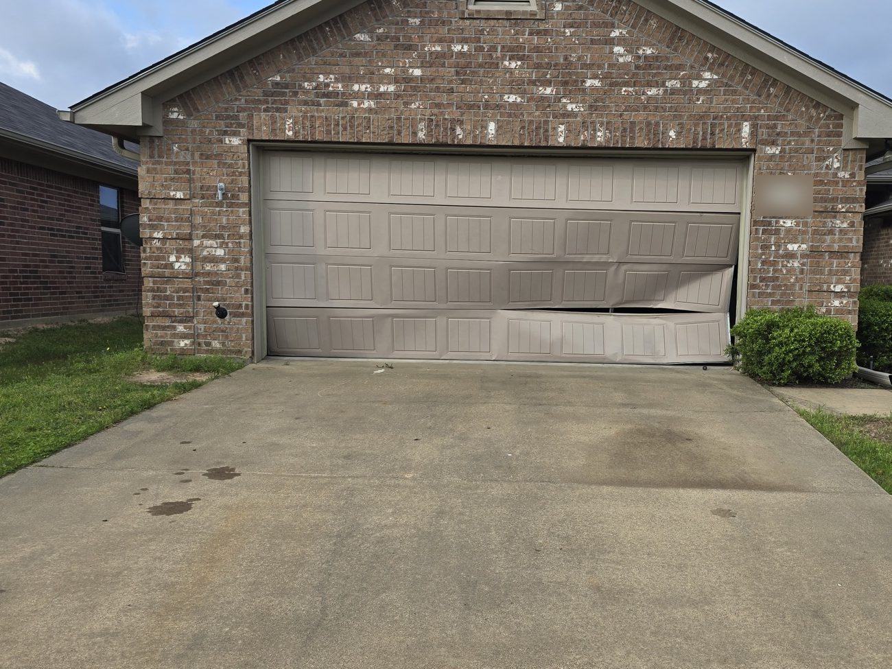 A bent garage door pushed off its track, before the repair