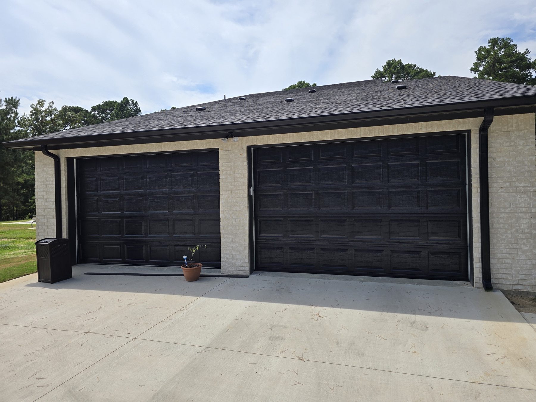 Two dark carriage-style garage doors on a brick home